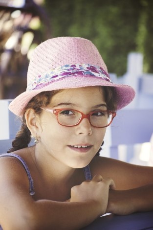 A little girl wearing pink hat and red glasses