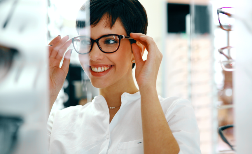 A woman smiling and holding her spectacles